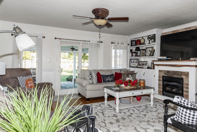 living room with ceiling fan, light wood-type flooring, and a tiled fireplace