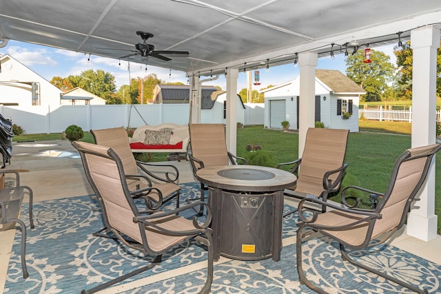 view of patio / terrace featuring a fire pit, ceiling fan, and an outbuilding