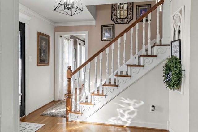 entrance foyer with an inviting chandelier, ornamental molding, and hardwood / wood-style flooring