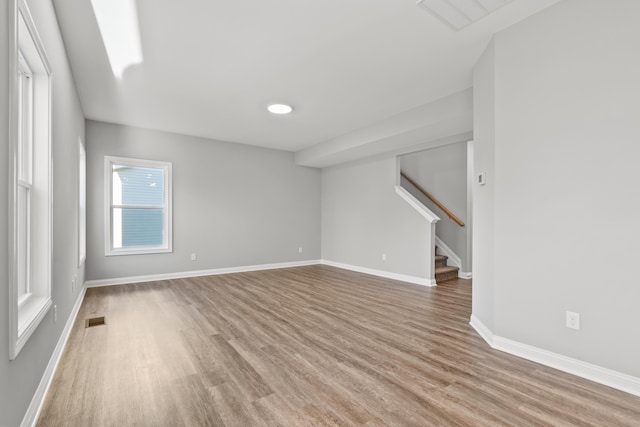 spare room with light wood-type flooring, visible vents, stairway, and baseboards