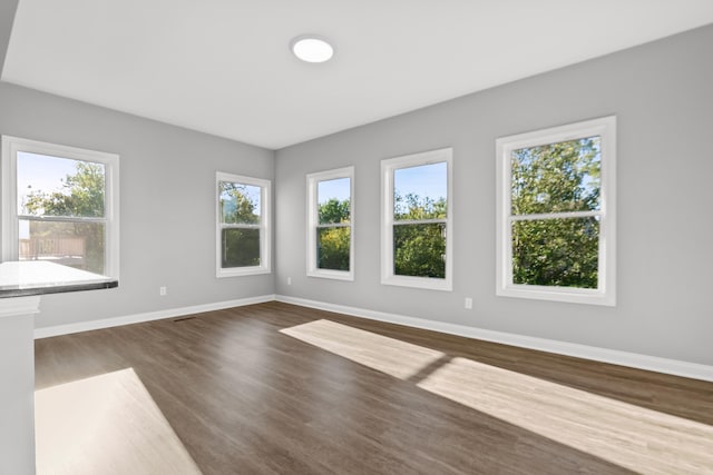 unfurnished room with dark wood-style floors and baseboards