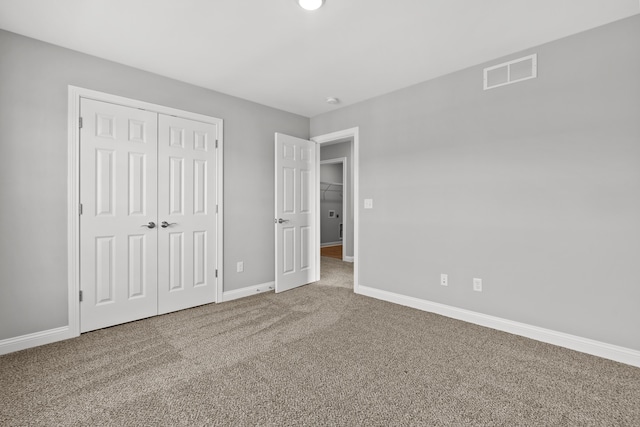 unfurnished bedroom with a closet, carpet flooring, visible vents, and baseboards