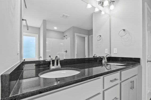 full bath with double vanity, visible vents, a shower, and a sink