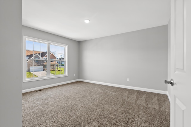 carpeted spare room with visible vents and baseboards