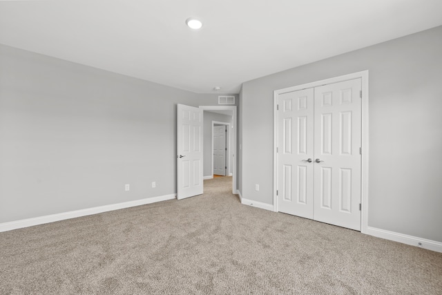 unfurnished bedroom featuring carpet, a closet, visible vents, and baseboards