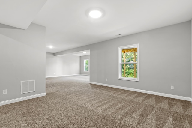 unfurnished room with carpet, visible vents, and baseboards