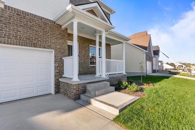 view of exterior entry with a porch, an attached garage, brick siding, concrete driveway, and a lawn