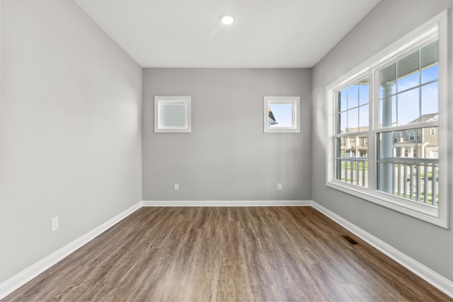 spare room with visible vents, baseboards, and wood finished floors