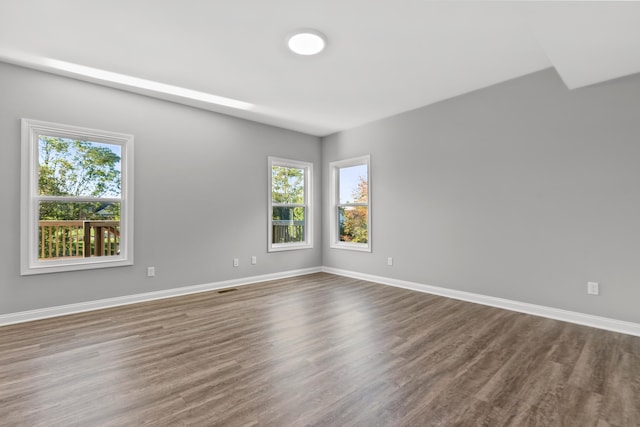 unfurnished room featuring dark wood-style floors, visible vents, and baseboards