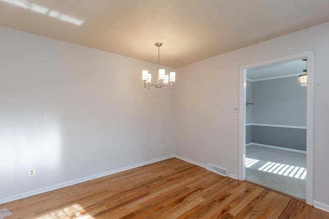 unfurnished room featuring a notable chandelier, hardwood / wood-style flooring, and ornamental molding