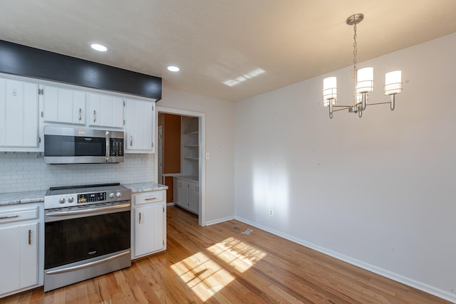 kitchen with appliances with stainless steel finishes, light hardwood / wood-style flooring, white cabinetry, and pendant lighting