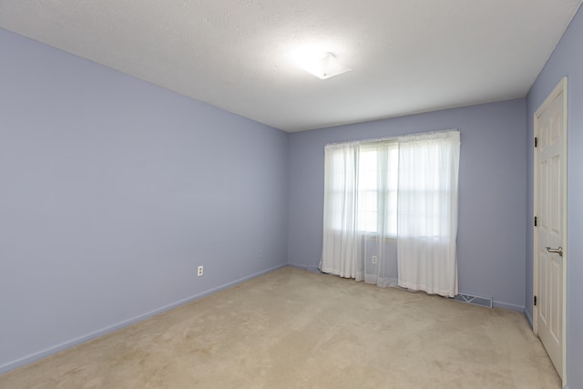 spare room with light carpet and a textured ceiling