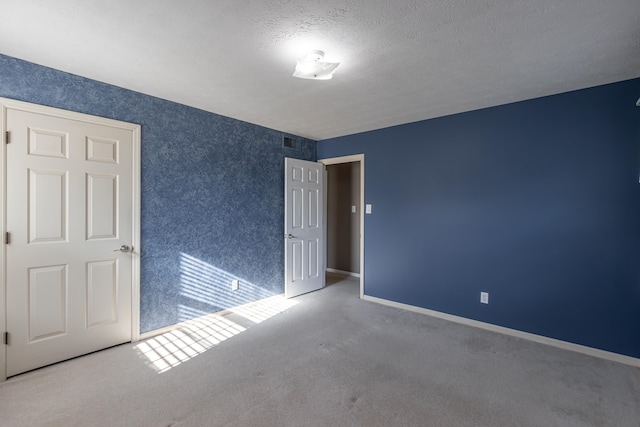 unfurnished bedroom with a textured ceiling and carpet floors