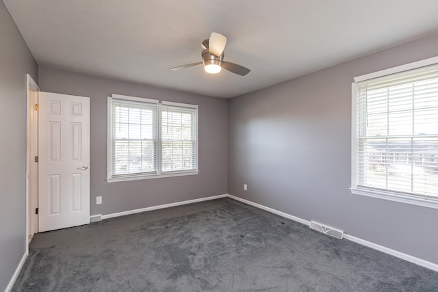 unfurnished room with dark colored carpet and ceiling fan