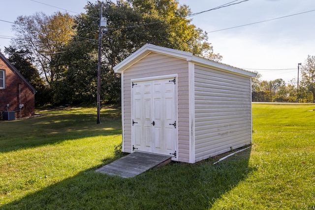 view of outdoor structure featuring a yard and central air condition unit