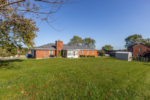 rear view of property featuring a storage shed and a lawn