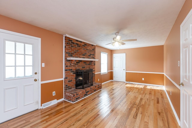 unfurnished living room with ceiling fan, hardwood / wood-style flooring, a textured ceiling, and a fireplace