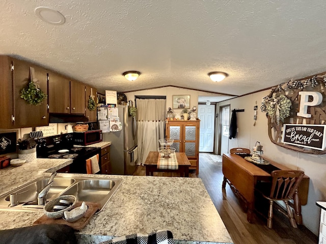 kitchen featuring dark wood-type flooring, vaulted ceiling, sink, black appliances, and a textured ceiling