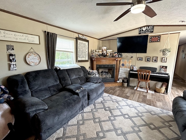 living room featuring ceiling fan, wood-type flooring, crown molding, lofted ceiling, and a textured ceiling