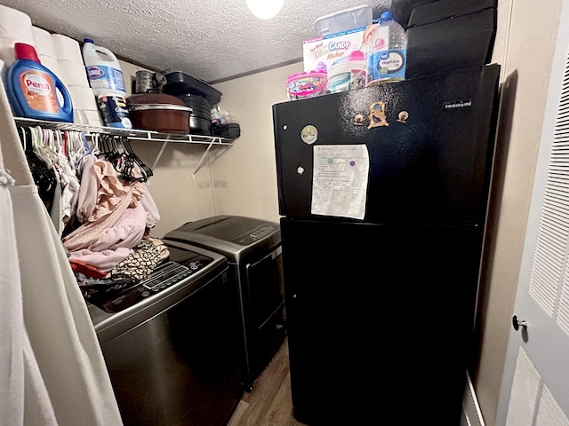 laundry area with a textured ceiling, washing machine and clothes dryer, and hardwood / wood-style flooring