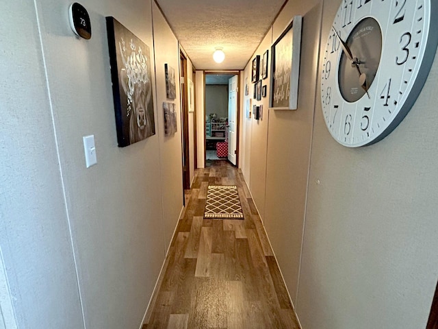 corridor with a textured ceiling and hardwood / wood-style flooring