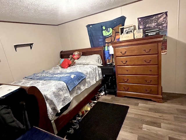 bedroom with a textured ceiling, crown molding, and light hardwood / wood-style floors