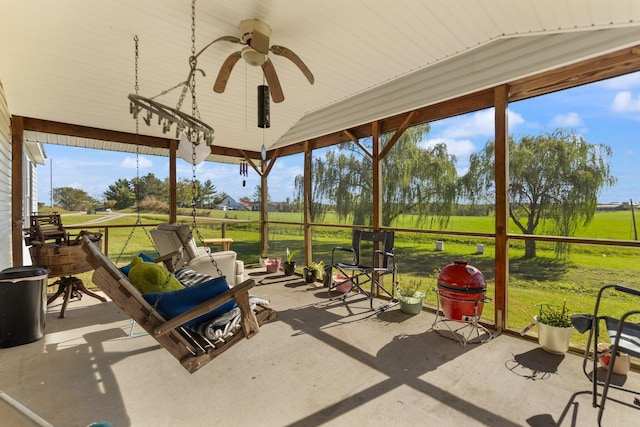 sunroom featuring lofted ceiling, ceiling fan, and a rural view