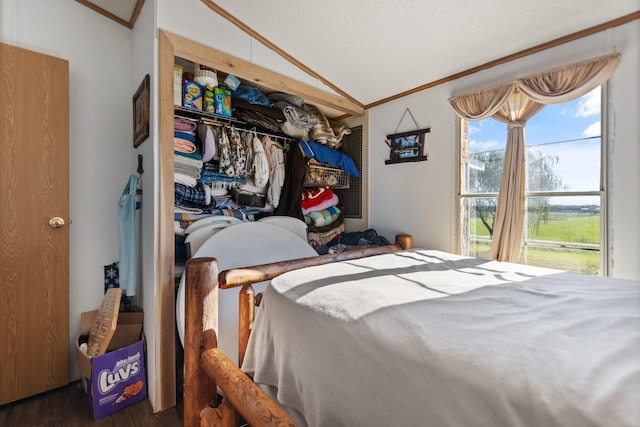 bedroom with crown molding, dark wood-type flooring, a closet, lofted ceiling, and a textured ceiling