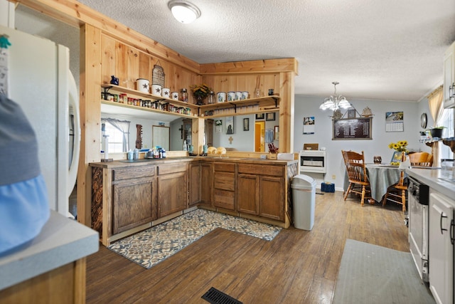 kitchen featuring dark hardwood / wood-style flooring, pendant lighting, a notable chandelier, ornamental molding, and a textured ceiling