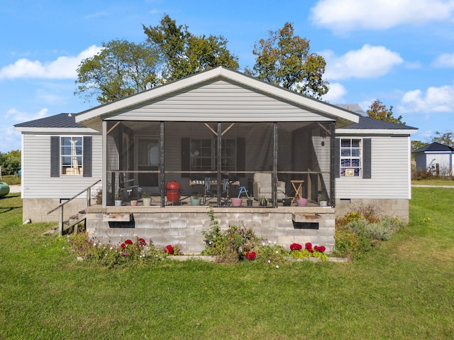 rear view of house featuring a yard and a sunroom