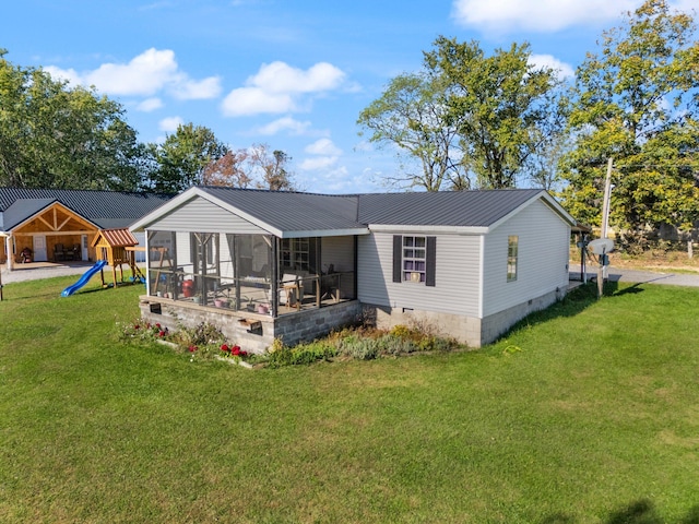 rear view of property featuring a playground, a sunroom, and a yard