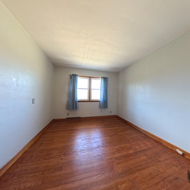 empty room with baseboards and wood finished floors