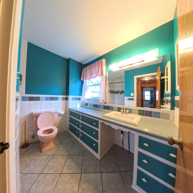 full bathroom with tile patterned flooring, toilet, a wainscoted wall, a sink, and tile walls