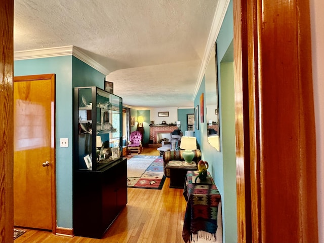 hall with crown molding, a textured ceiling, and light wood-type flooring