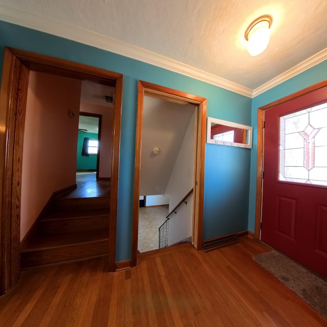 entrance foyer featuring a textured ceiling, baseboards, wood finished floors, and crown molding