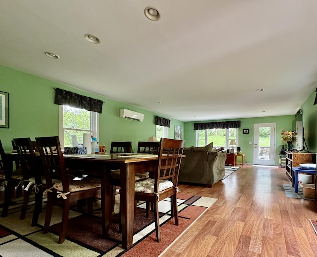 dining room with light wood-style flooring, a wall unit AC, a wealth of natural light, and recessed lighting