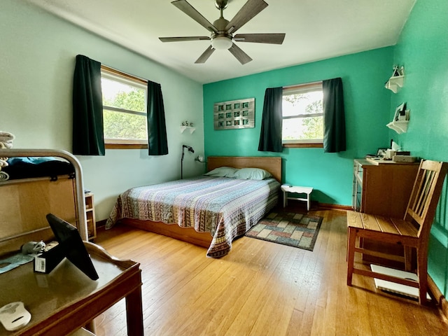 bedroom with multiple windows, ceiling fan, and wood finished floors