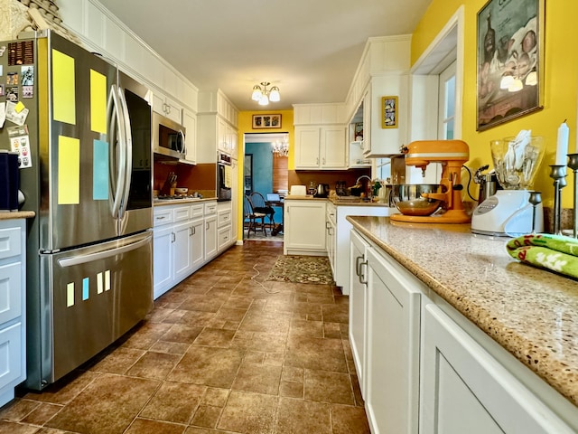 kitchen featuring stainless steel appliances, stone finish flooring, white cabinets, a sink, and light stone countertops