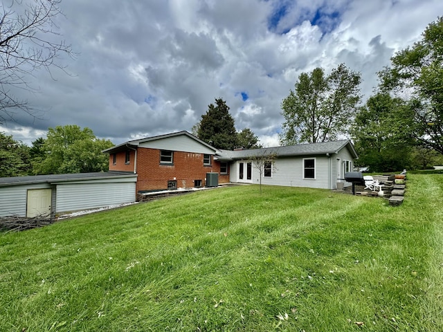 back of property featuring brick siding, central AC, and a yard