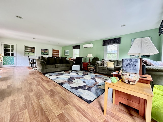 living area with a wall mounted air conditioner, light wood-style flooring, and recessed lighting