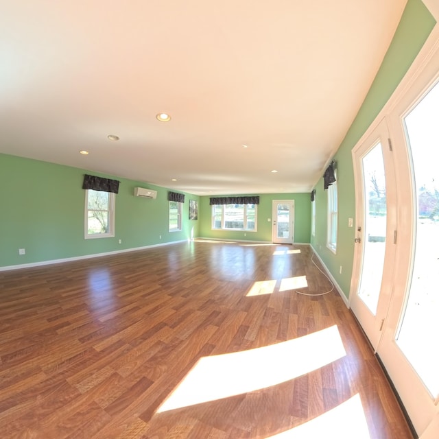 unfurnished living room featuring recessed lighting, baseboards, wood finished floors, and a wall mounted air conditioner