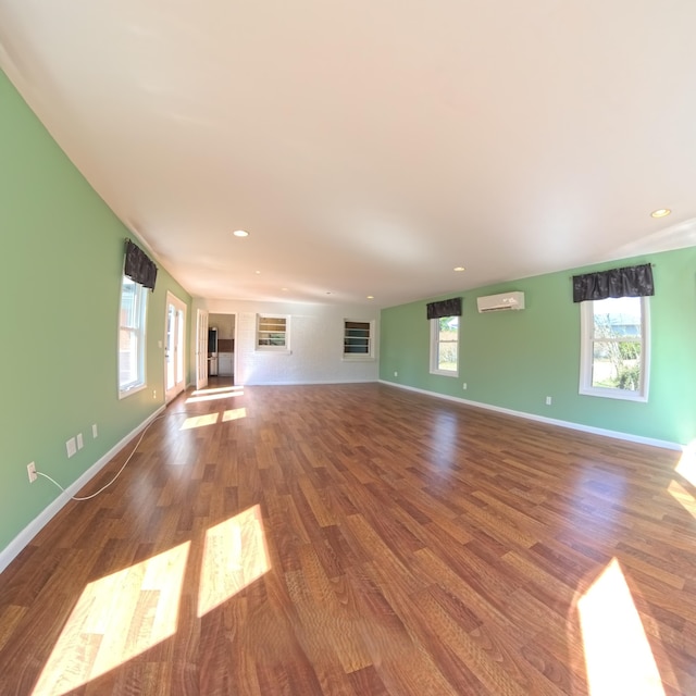 unfurnished living room with baseboards, wood finished floors, and a wall mounted air conditioner