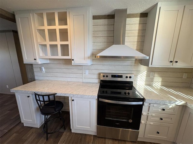 kitchen featuring wall chimney exhaust hood, white cabinetry, and stainless steel range with electric cooktop