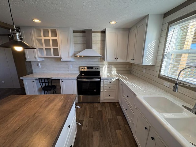 kitchen featuring sink, electric stove, white cabinetry, and wall chimney range hood