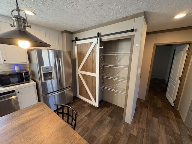 kitchen featuring white cabinets, appliances with stainless steel finishes, a barn door, and dark hardwood / wood-style floors