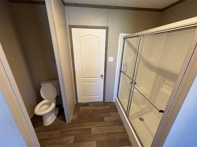 bathroom with toilet, a shower with door, and hardwood / wood-style flooring