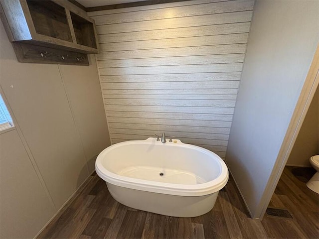 bathroom with hardwood / wood-style flooring, toilet, and wooden walls