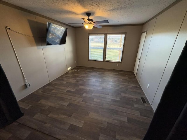 unfurnished bedroom with a textured ceiling, ceiling fan, crown molding, and dark wood-type flooring