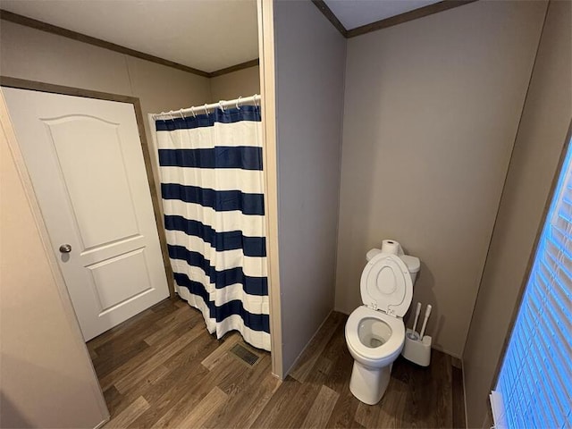 bathroom with hardwood / wood-style flooring, toilet, ornamental molding, and walk in shower