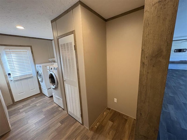 clothes washing area with independent washer and dryer, a textured ceiling, crown molding, and hardwood / wood-style floors